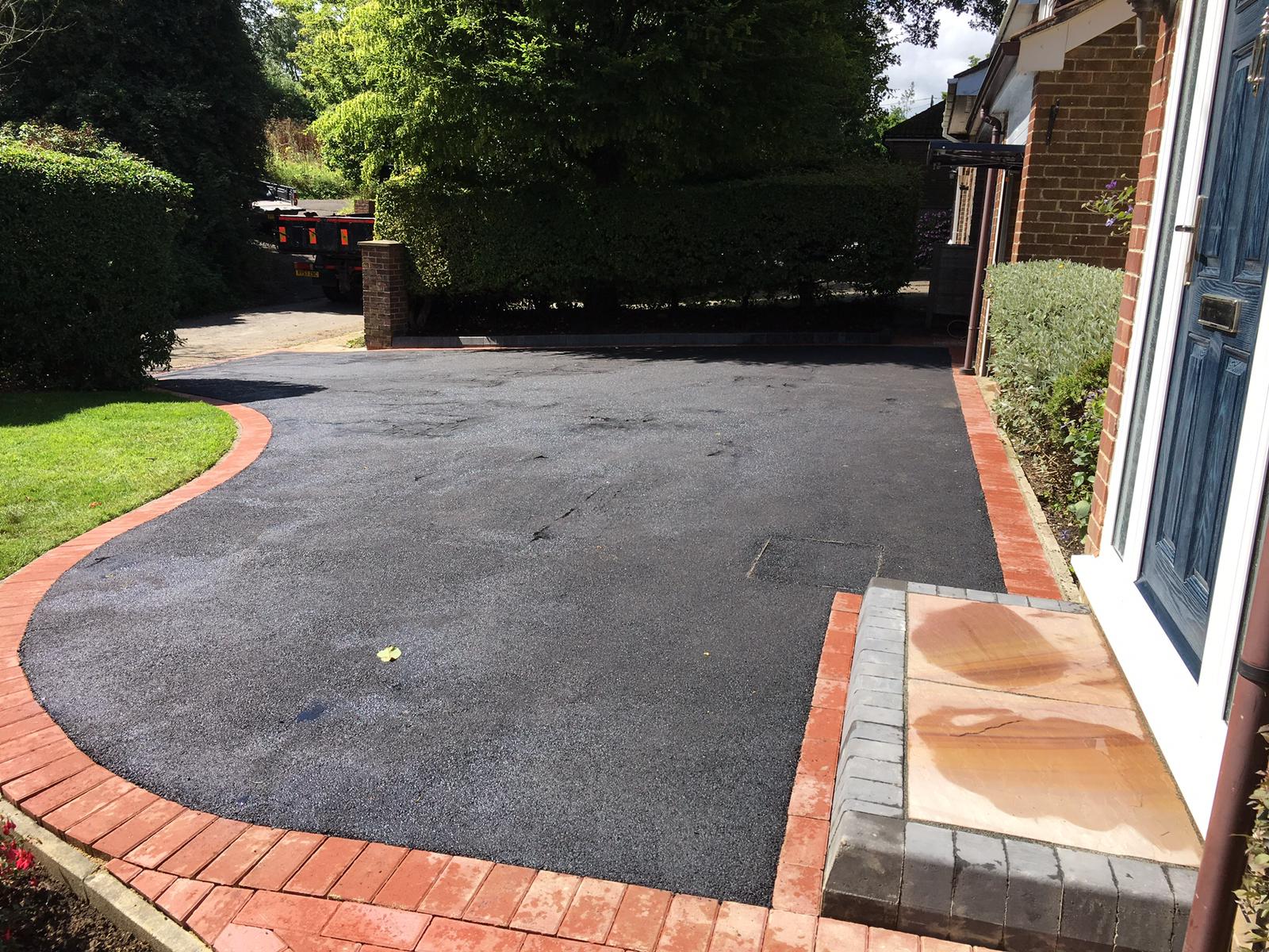 Tarmac drive with red brick border and sandstone step